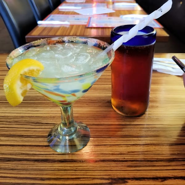 Margarita with a lemon slice and a beer on a wooden table at Mexicali Blue.