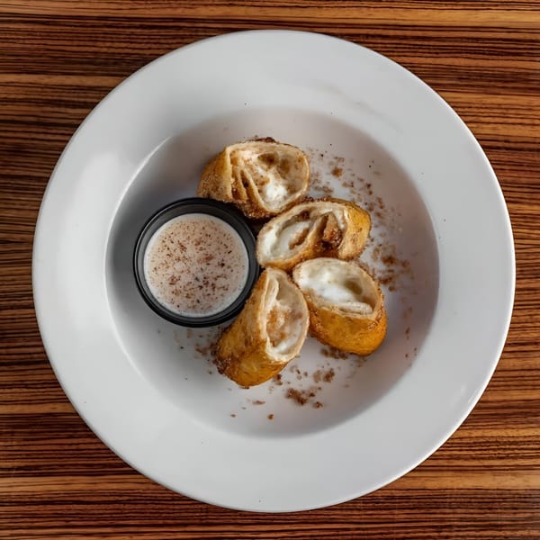 Four Mexicali Blue dessert chimichangas with cream cheese filling and a side of dipping sauce.